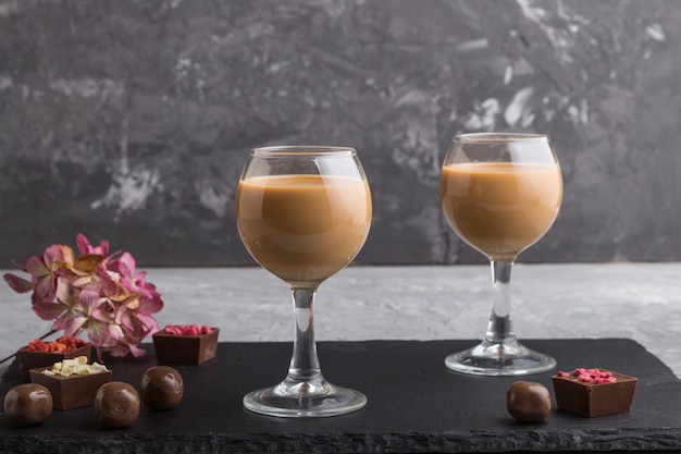 Liqueur de chocolat sucré en verre et ardoise en pierre noire. Vue de côté