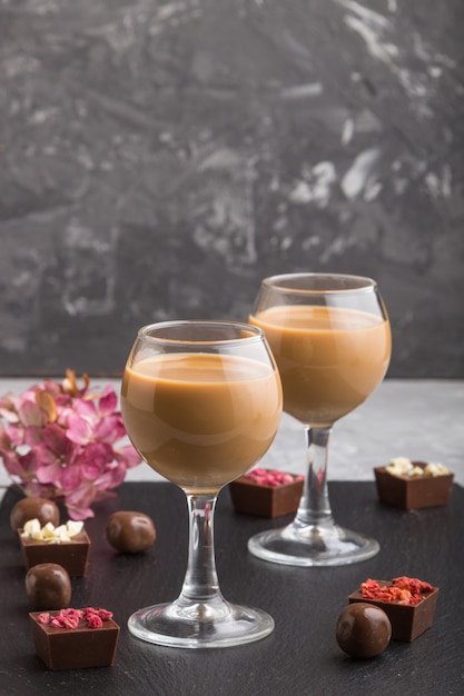 Liqueur de chocolat sucré en verre et ardoise en pierre noire. Vue de côté