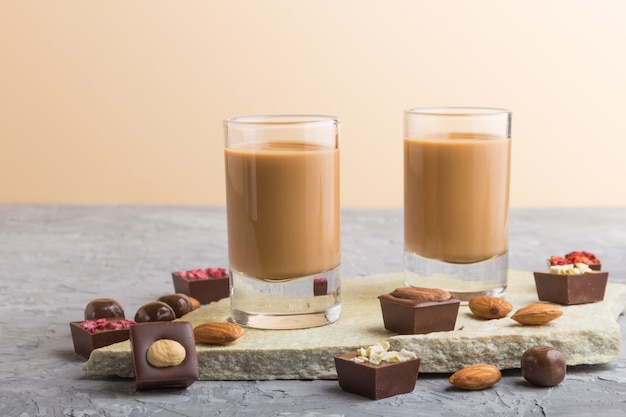 Liqueur de chocolat sucré en verre sur une surface en béton gris et ardoise en pierre. Vue de côté.