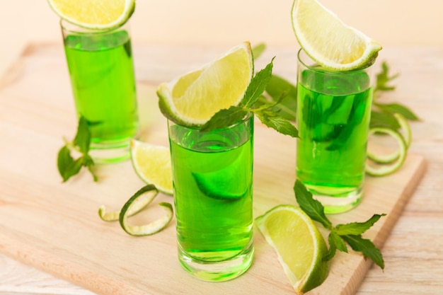 Liqueur de menthe douce et rafraîchissante avec de la glace et des feuilles de menthe sur fond de table Coups avec tranche de citron vert et mise à plat de menthe