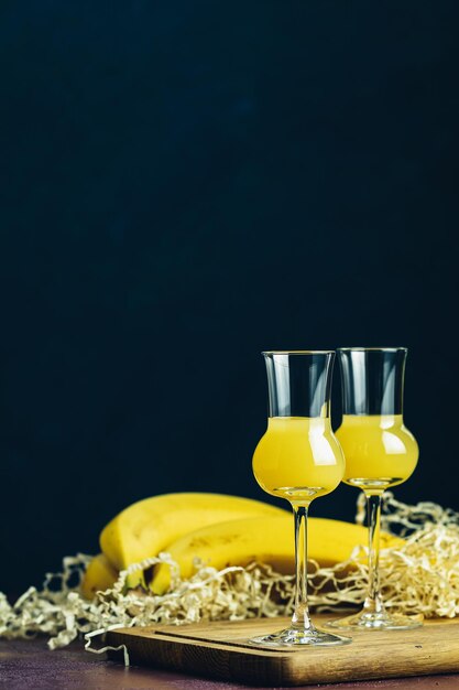 Liqueurs aromatisées à la banane que les Français appellent crème de banane dans un verre à grappas sur une surface en béton foncé Boisson apéritive européenne Mise au point sélective faible profondeur de l'espace de copie des champs