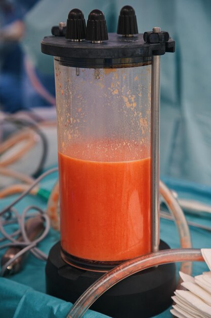 Photo un liquide orange sanguine est versé dans un cylindre.