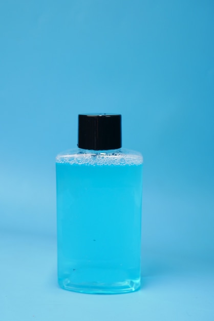 Liquide de rince-bouche dans un récipient sur fond bleu