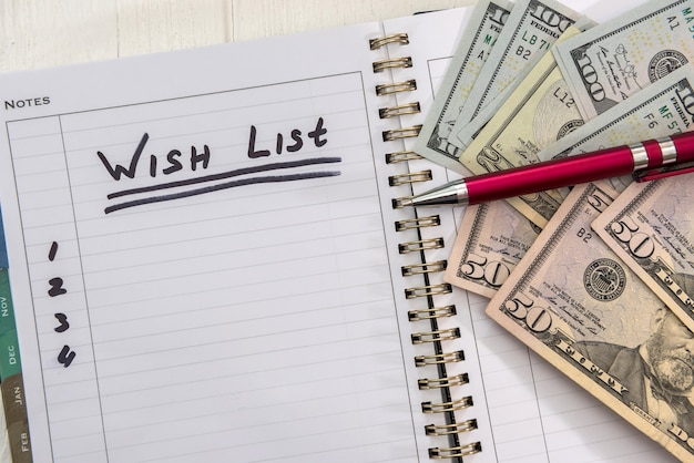 Liste de souhaits de texte sur le bloc-notes avec des billets d'un dollar. planifier pour l'avenir