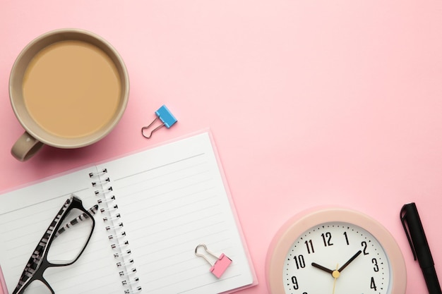 Liste de tâches écrite dans un cahier Bloc-notes avec une liste de tâches sur rose avec une tasse de café et une horloge