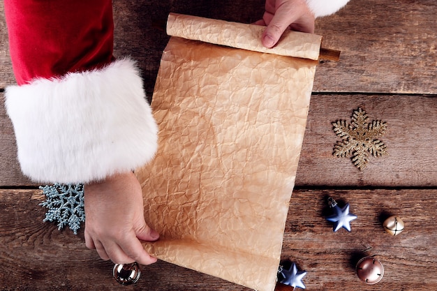 Une liste de vœux de Noël dans les mains du Père Noël sur une surface en bois