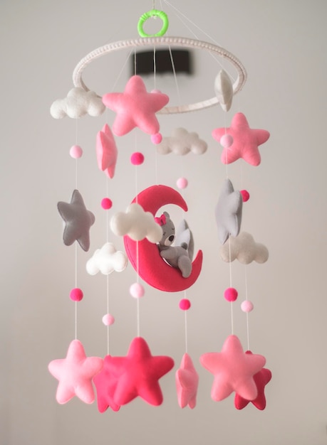 Lit de bébé suspendu Lit de feutre mobile avec des étoiles en peluche douces nuages et lune avec un peluche endormi Lit isolé contre un fond de couleur neutre Joli jouet de musique sur le berceau dans la chambre du bébé