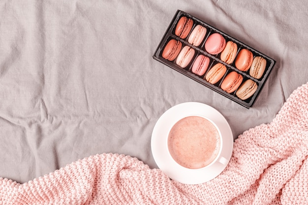 Lit avec café à carreaux en tricot rose et macarons