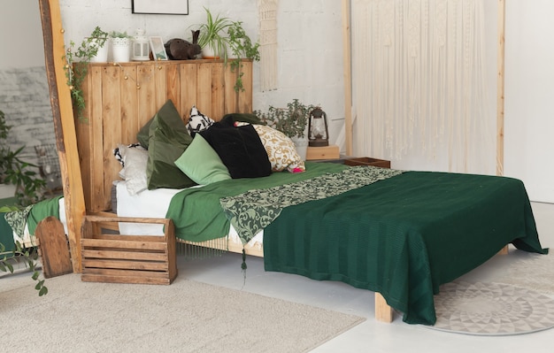 Lit confortable avec de nouveaux draps verts à l'intérieur de la chambre de style écologique