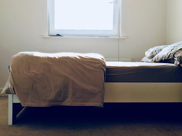 Photo le lit contre la fenêtre de la chambre.