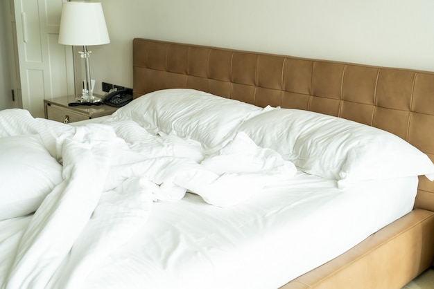Lit en désordre avec oreiller blanc et couverture sur lit