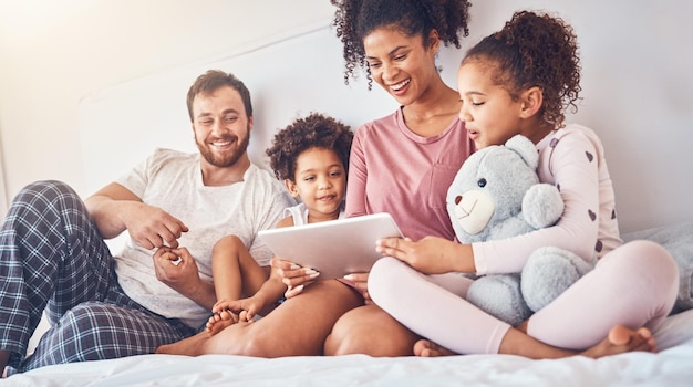 Lit de famille heureux et tablette diffusant des films ou des jeux tout en se détendant et en jouant dans leur maison Abonnement en ligne et enfants avec parents dans une chambre pour se divertir et regarder