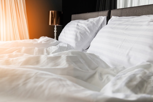 lit froissé défait avec des oreillers blancs malpropres dans la lumière du matin intérieur de la chambre