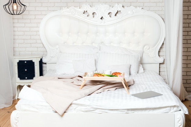 Lit avec ordinateur portable et petit-déjeuner, pigiste ou blogueur à la maison. Travaillez à l'ordinateur à la maison, le matin et l'heure du petit déjeuner