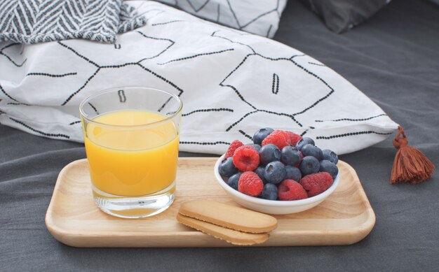 Lit de petit déjeuner Plateau en bois Intérieur matinal avec draps géométriques et taie d'oreiller Baies Jus d'orange