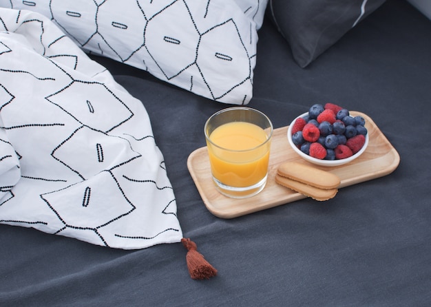 Lit de petit déjeuner Plateau en bois Intérieur matinal avec draps géométriques et taie d'oreiller Baies Jus d'orange