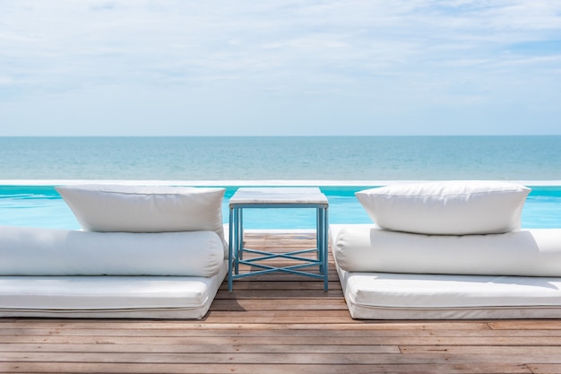 Lit de plage blanc à la piscine extérieure mer turquoise