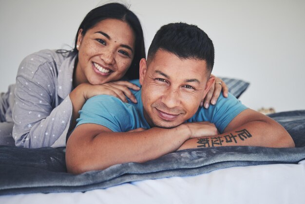 Lit portrait ou couple heureux à la maison avec soin ou soutien amoureux tout en créant des liens pour se détendre ensemble à la maison Homme ou femme du matin couché dans la chambre avec sourire, paix ou loyauté dans l'engagement du mariage