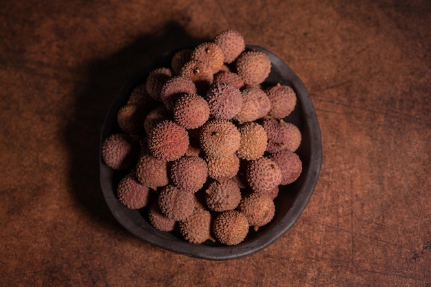 Litchi séché dans un bol sur une table jaune foncé ;