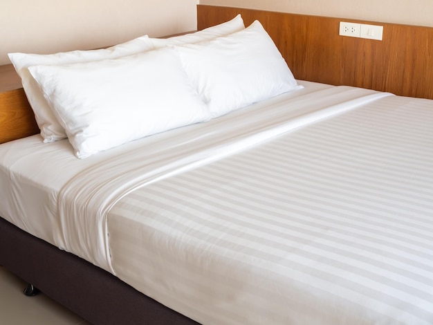 Literie blanche propre avec quatre oreillers blancs dans la chambre d'hôtel