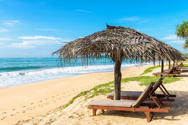 Lits de plage avec parasol sur la plage tropicale