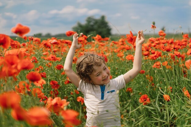 Little Boy joue dans un magnifique champ de coquelicots rouges.