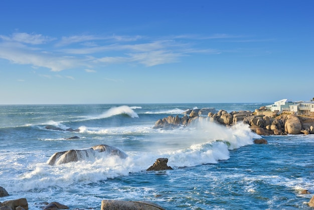 Un littoral rocheux dans la province du Cap en Afrique du Sud Les vagues de l'océan se brisent sur les rochers côtiers par une journée d'été ensoleillée avec un ciel bleu clair et un paysage tropical pittoresque en bord de mer dans le Western Cape