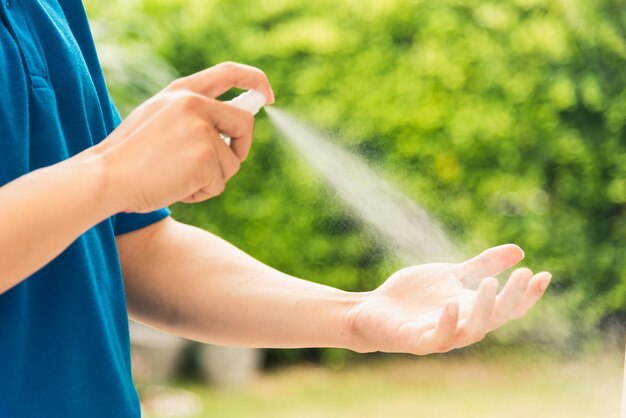 Livraison asiatique par courrier express jeune homme utilise un spray stérilisé avant de donner des boîtes à une cliente recevant à la fois un masque protecteur, sous couvre-feu coronavirus pandémique de quarantaine COVID-19