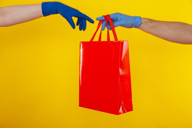 Livraison au moment de la quarantaine. Une personne donne le sac rouge à une autre personne.