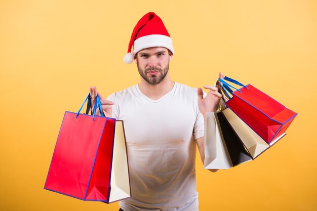 Livraison de cadeaux de Noël. Le matin avant Noël. joyeux père Noël sur fond jaune. achats de Noël en ligne. Bonne année. l'homme au bonnet de noel tient un cadeau de noël. Es-tu prêt.