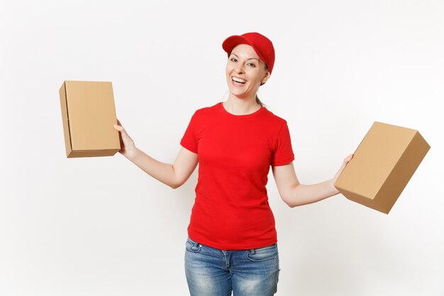 Livraison femme souriante en uniforme rouge isolé sur fond blanc. Femme en casquette, t-shirt, jeans travaillant comme coursier ou revendeur tenant des boîtes en carton. Réception du colis. Copiez l'espace pour la publicité.