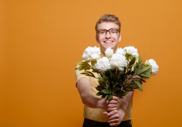 Livraison de fleurs, homme avec des fleurs sur fond jaune