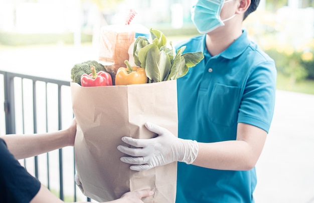 Livraison Un homme asiatique porte un masque de protection en uniforme bleu et prêt à envoyer le sac de nourriture