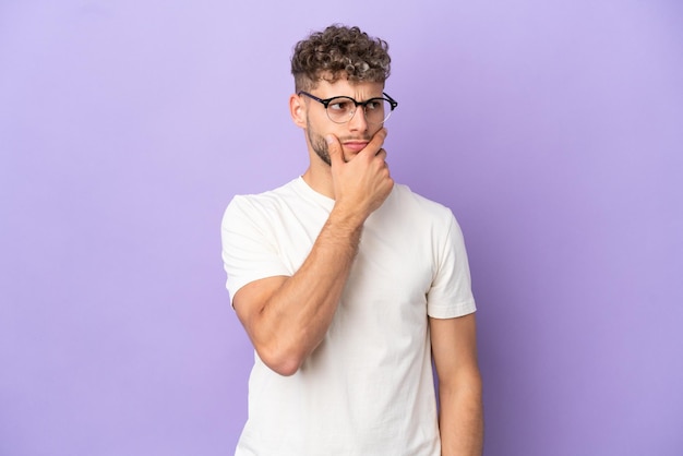 Livraison homme caucasien isolé sur fond violet ayant des doutes et avec une expression de visage confuse