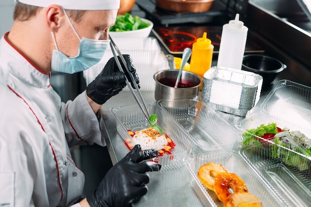 Livraison de nourriture au restaurant. Le chef prépare les plats au restaurant et les emballe dans des plats jetables.