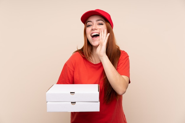 Livraison de pizza adolescent fille tenant une pizza sur un mur isolé criant avec la bouche grande ouverte