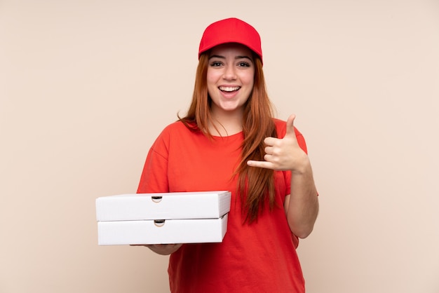 Livraison de pizza adolescente fille tenant une pizza sur un mur isolé faisant un geste de téléphone