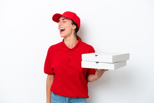 Livraison de pizza femme caucasienne avec uniforme de travail ramasser des boîtes à pizza isolées sur fond blanc en riant en position latérale