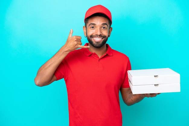 Livraison de pizza Homme brésilien avec uniforme de travail ramassant des boîtes de pizza isolées sur fond bleu faisant un geste de téléphone Appelez-moi signe de retour