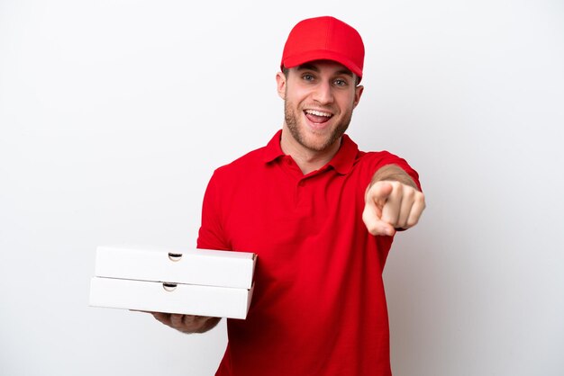 Livraison de pizza homme caucasien avec uniforme de travail ramasser des boîtes de pizza isolé sur fond blanc surpris et pointant vers l'avant