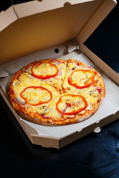 Livraison de pizza italienne. Délicieux plat de pizzeria cuit au four avec mozzarella, parmesan et fromage, livré dans une boîte en carton. Délicieuse restauration rapide à emporter cuite au four pour le dîner.