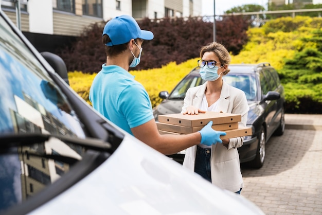 Livraison sûre - le coursier sur une camionnette apporte une pizza au client