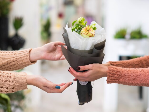 Livraison sûre et rapide de bouquets de fleurs pour quelqu'un que vous aimez. Mains de femmes tenant un arrangement créatif de roses dahlia et de baies