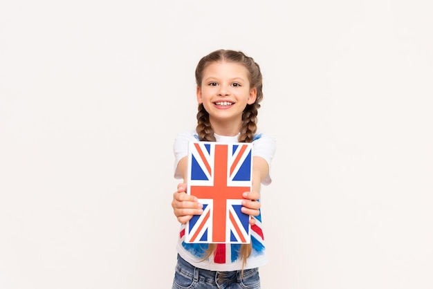 Un livre d'anglais est tenu par une petite fille avec le drapeau de la Grande-Bretagne sur son t-shirt Cours d'anglais pour enfants