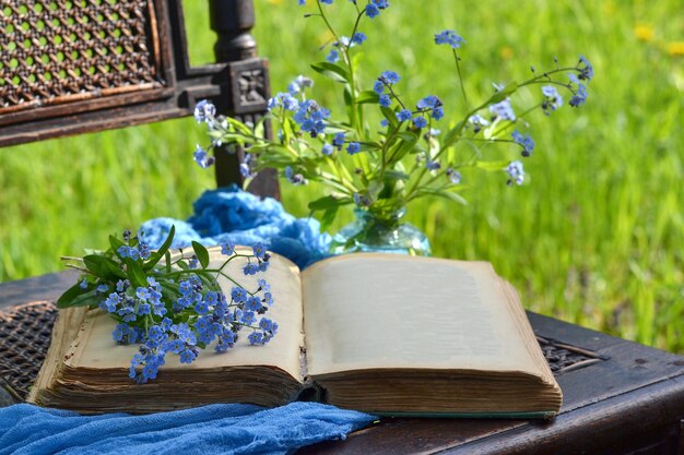 Un livre antique ouvert sur une chaise dans le jardin et des fleurs en arrière-plan