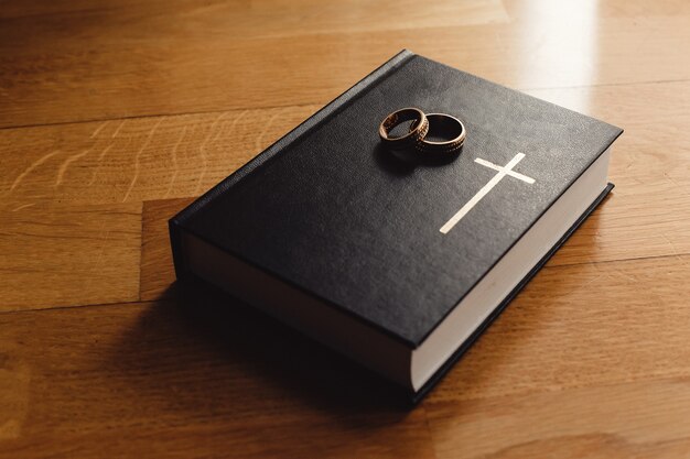 Livre de la Bible sur un plancher en bois. Deux petits anneaux sur la bible. La cérémonie du mariage.