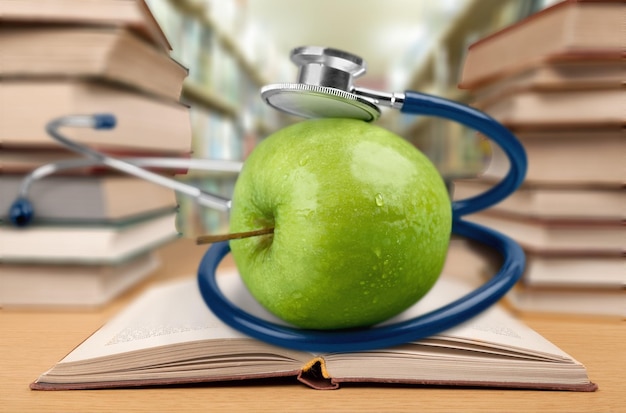 Livre en bibliothèque avec pomme et stéthoscope