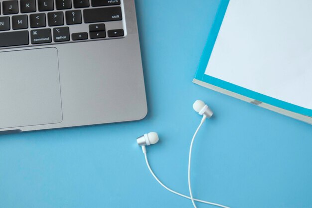 Livre blanc de casque et clavier d'ordinateur portable sur le fond bleu