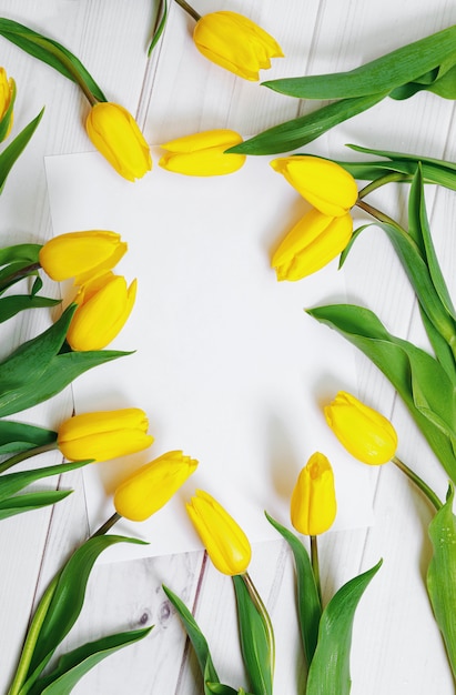 Livre blanc pour votre texte et bouquet de tulipes jaunes sur fond de bois. Concept de vacances.