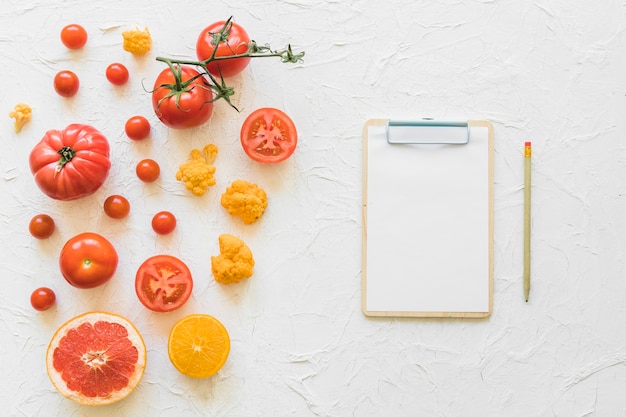 Photo livre blanc sur presse-papiers avec crayon et légumes sur fond texturé